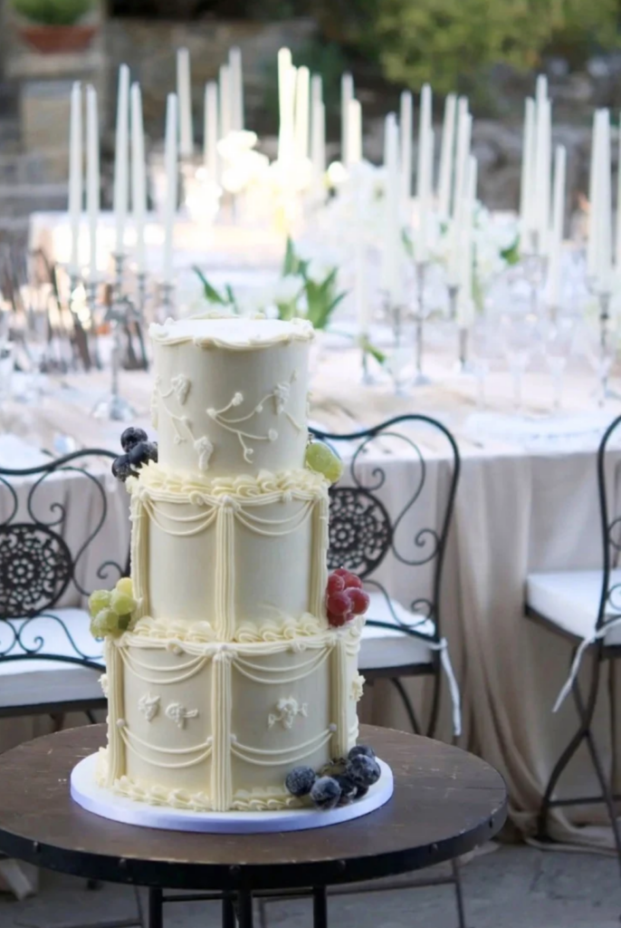 Three-tier vintage wedding cake in front of a candlelit wedding table at La Baronia