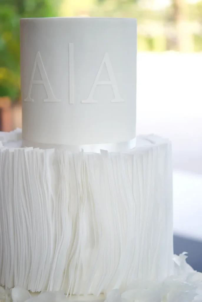 Close-up of a raised white-on-white monogram on a wedding cake