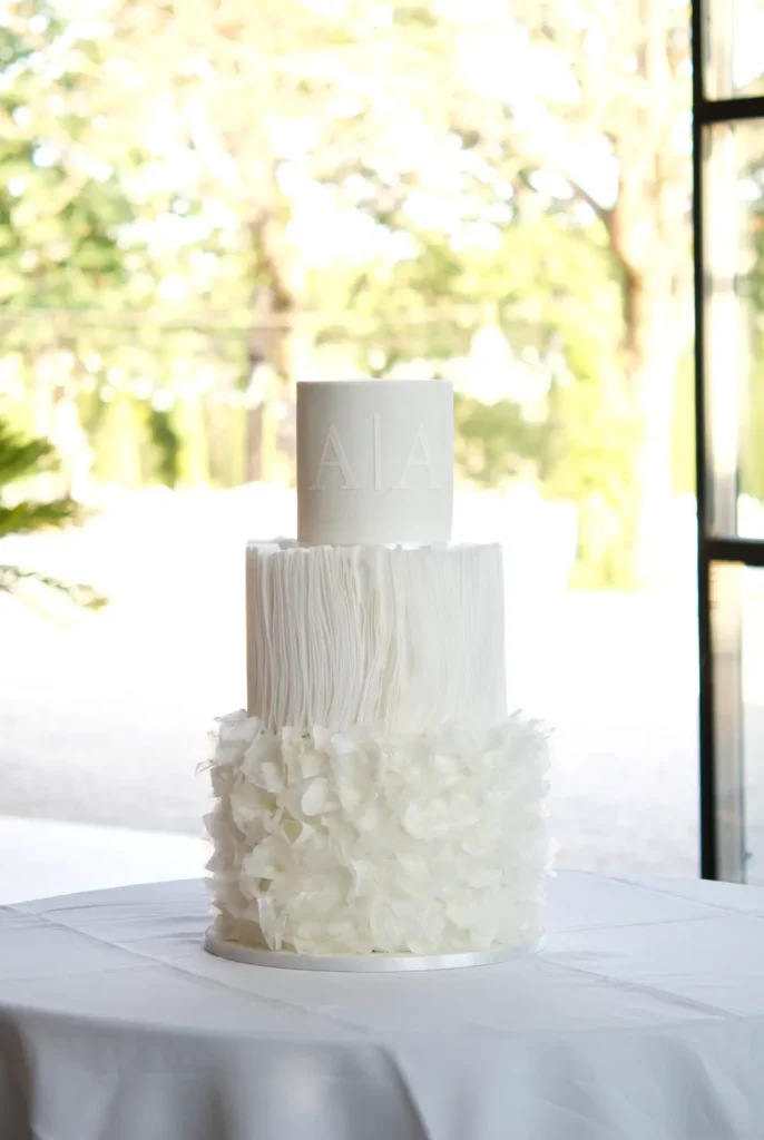 Wafer paper wedding cake in all white with a raised monogram at Castell de Sant Marçal