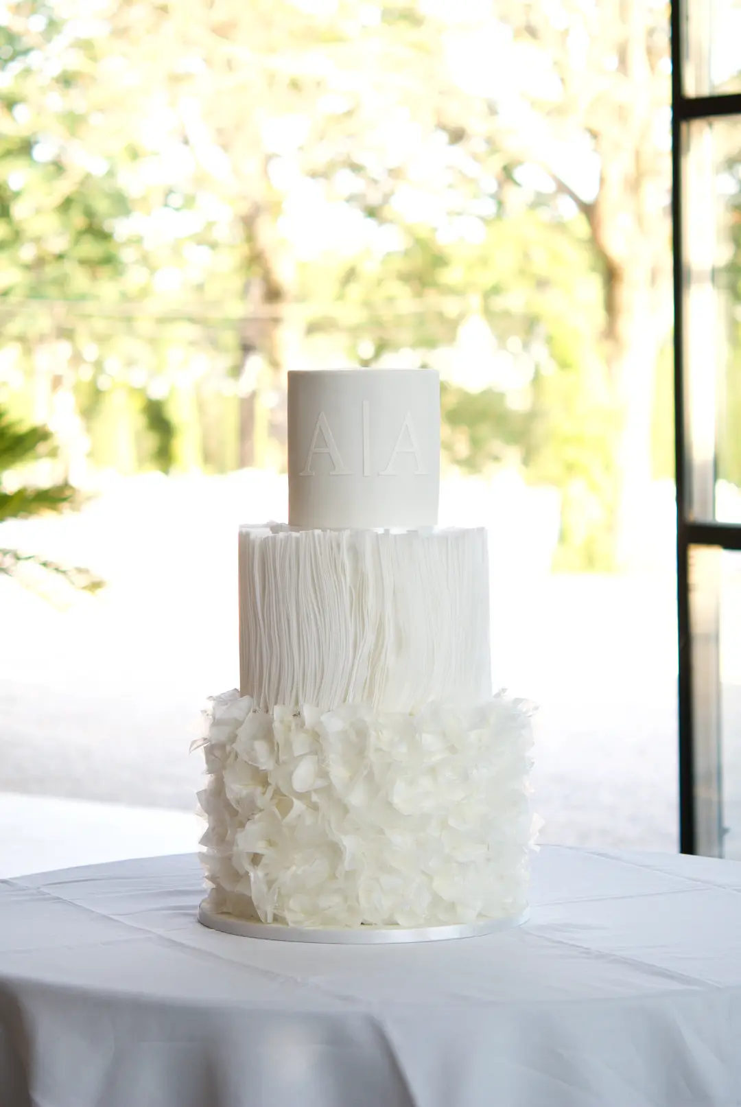 Wafer paper wedding cake in all white with a raised monogram at Castell de Sant Marçal