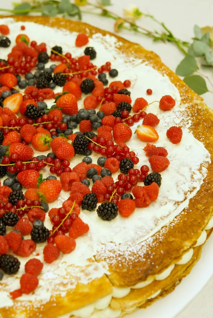 Close-up of berries and greenery on a millefoglie wedding cake by Mericakes