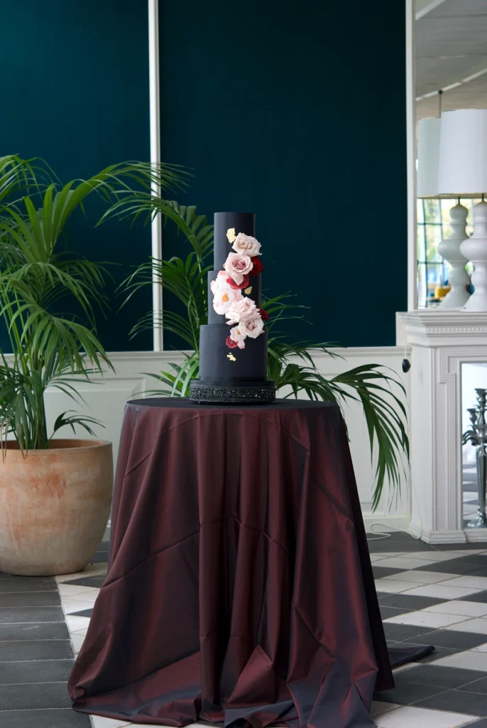 Black and gold wedding cake decorated with fresh roses