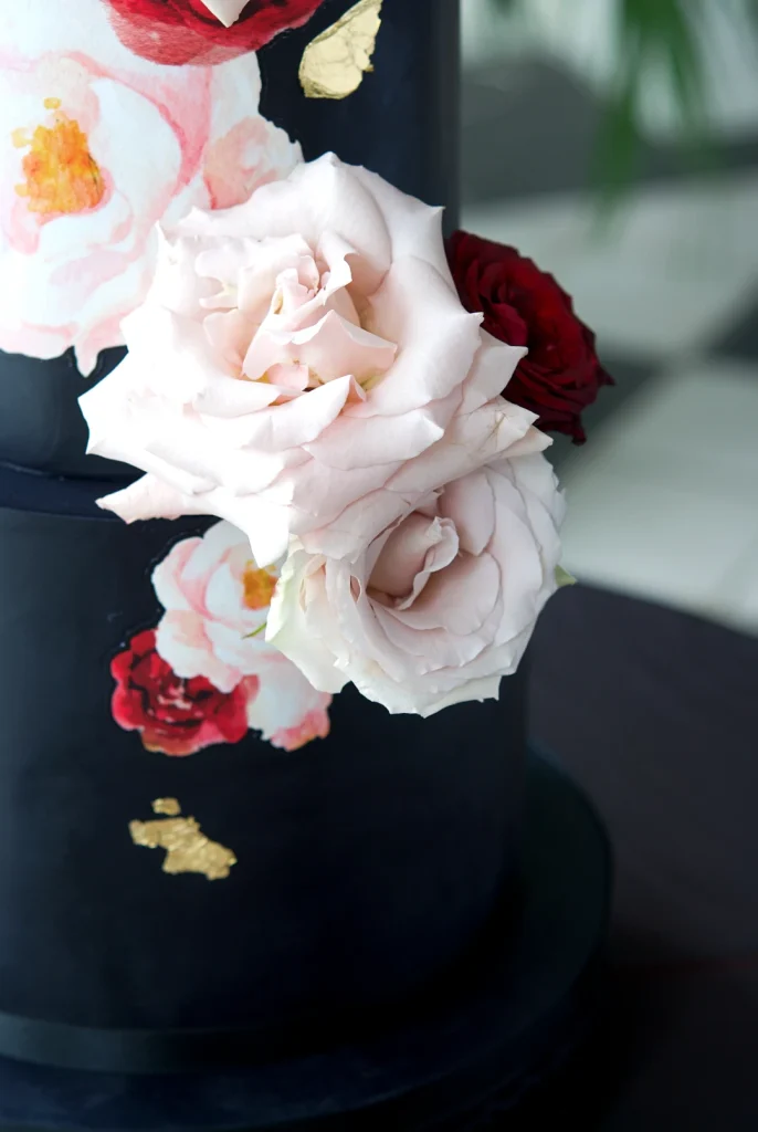 Close-up of watercolour roses on a black wedding cake