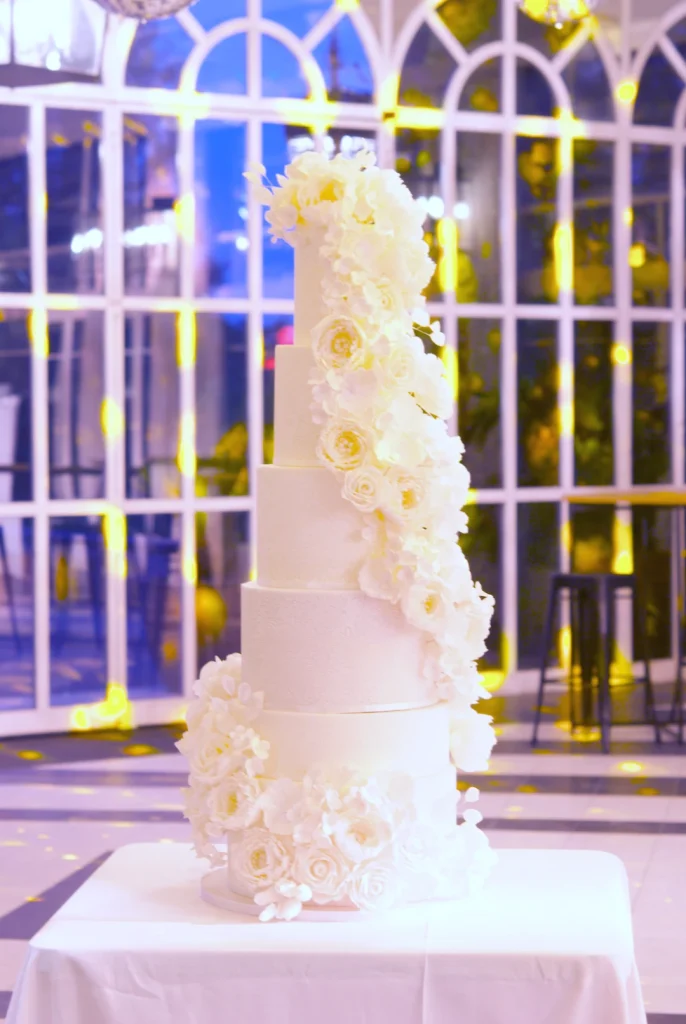 Six-tier lace wedding cake with a cascade of sugar flowers at Castell de Sant Marçal, Barcelona