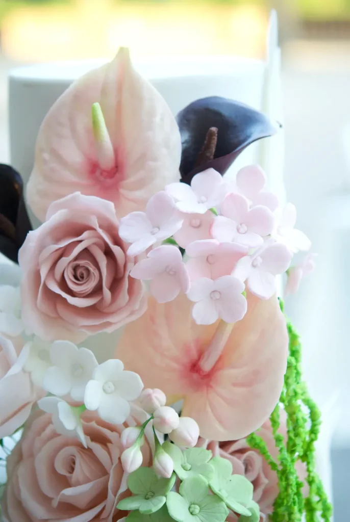 Detail of a pink sugar anthurium and roses, handcrafted petal by petal for a wedding cake