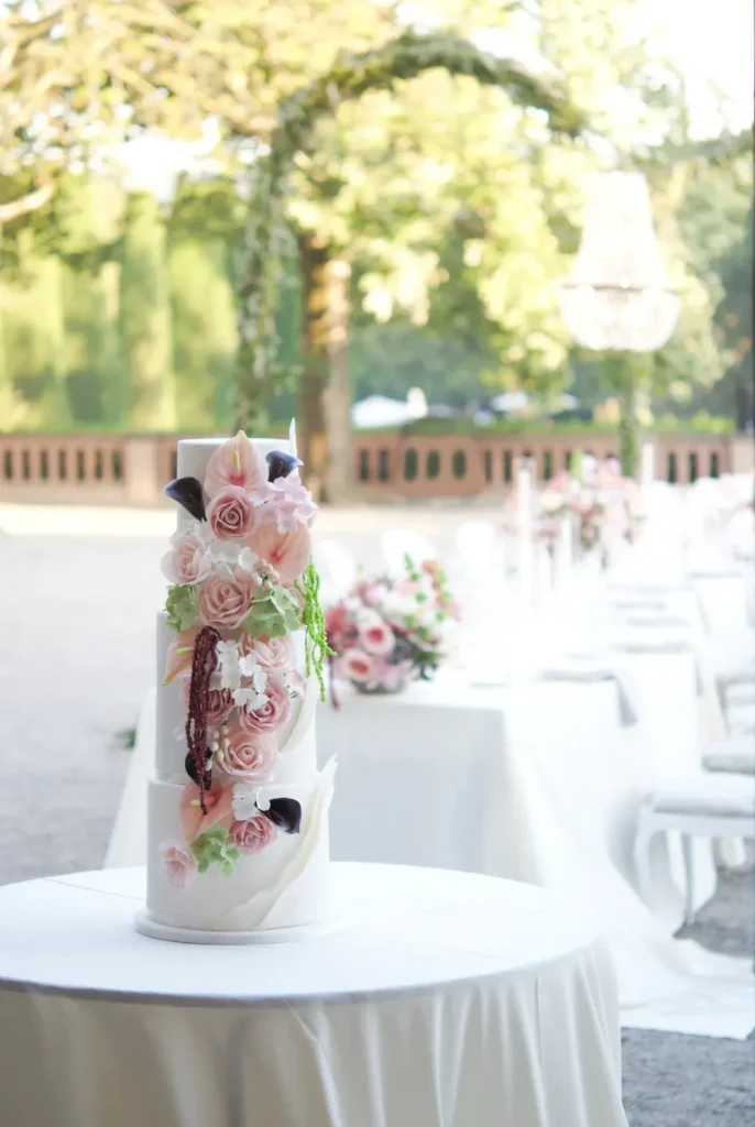 White four-tier wedding cake with sugar flowers at an outdoor wedding reception in Catalonia