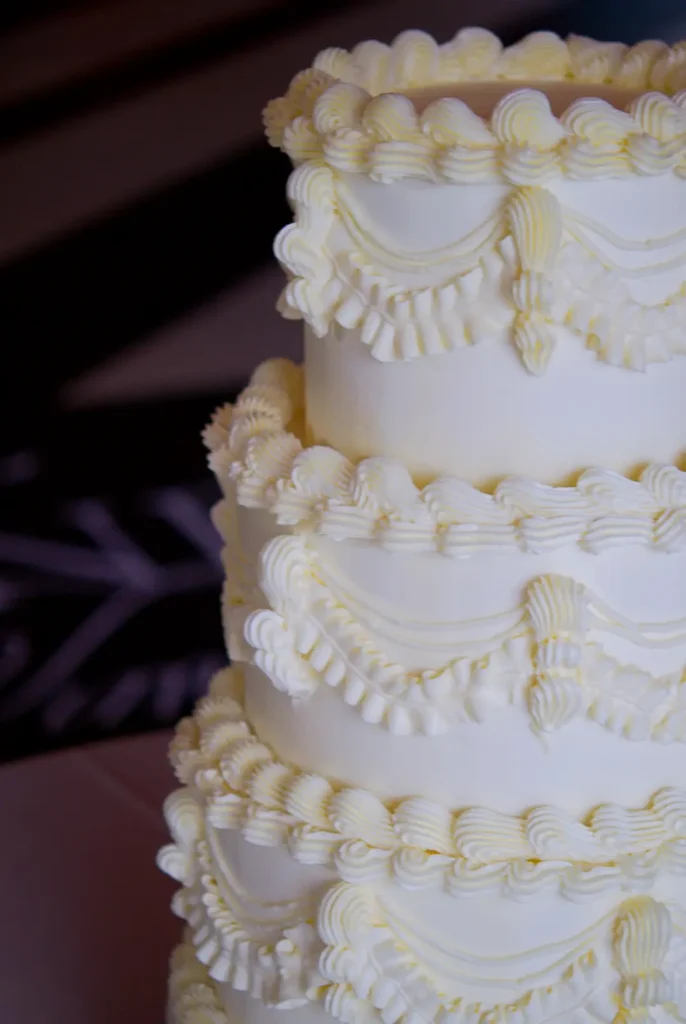 Close-up of hand-piped buttercream garlands and ruffles on a vintage wedding cake